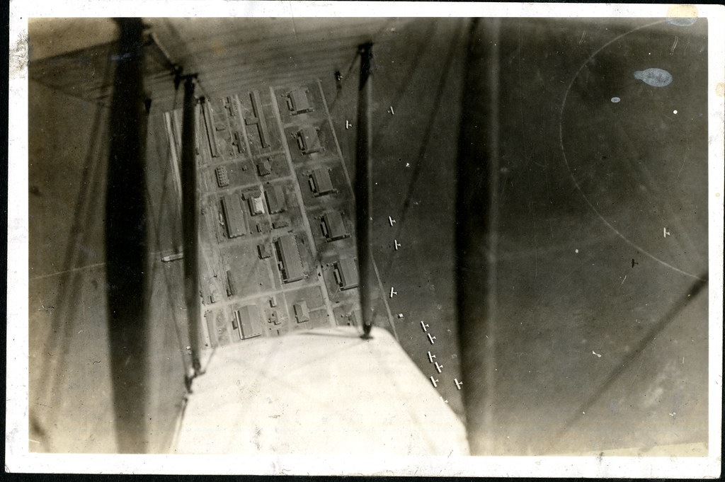 Aerial photograph of airfield looking down through wings of a biplane.