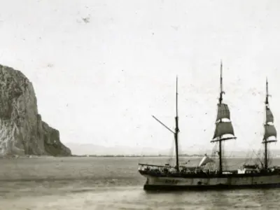 Sailing ship by a cliff.